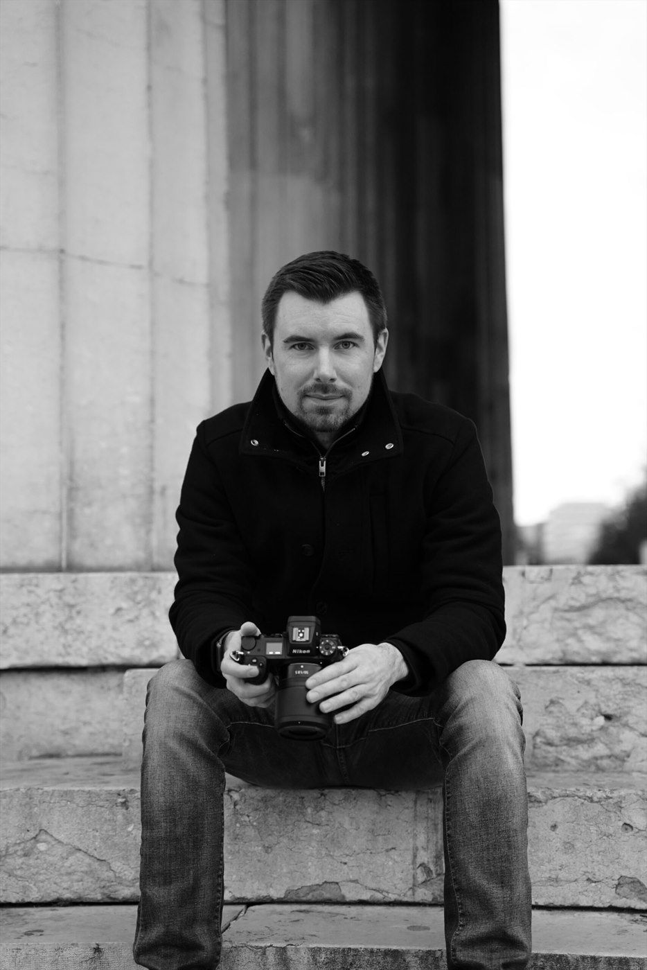 Andreas Sauer mit Kamera, sitzend auf einer Steintreppe